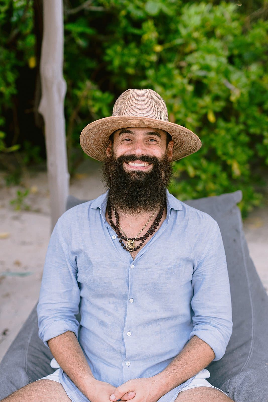 Emanuele Righes smiling outdoors, in a straw hat and a light blue shirt.
